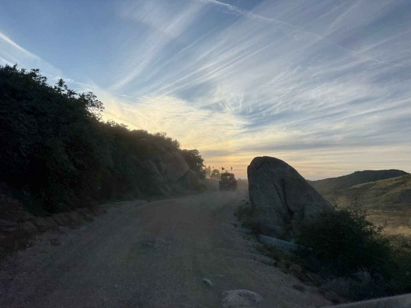 Dusty mountain road at sunrise with truck