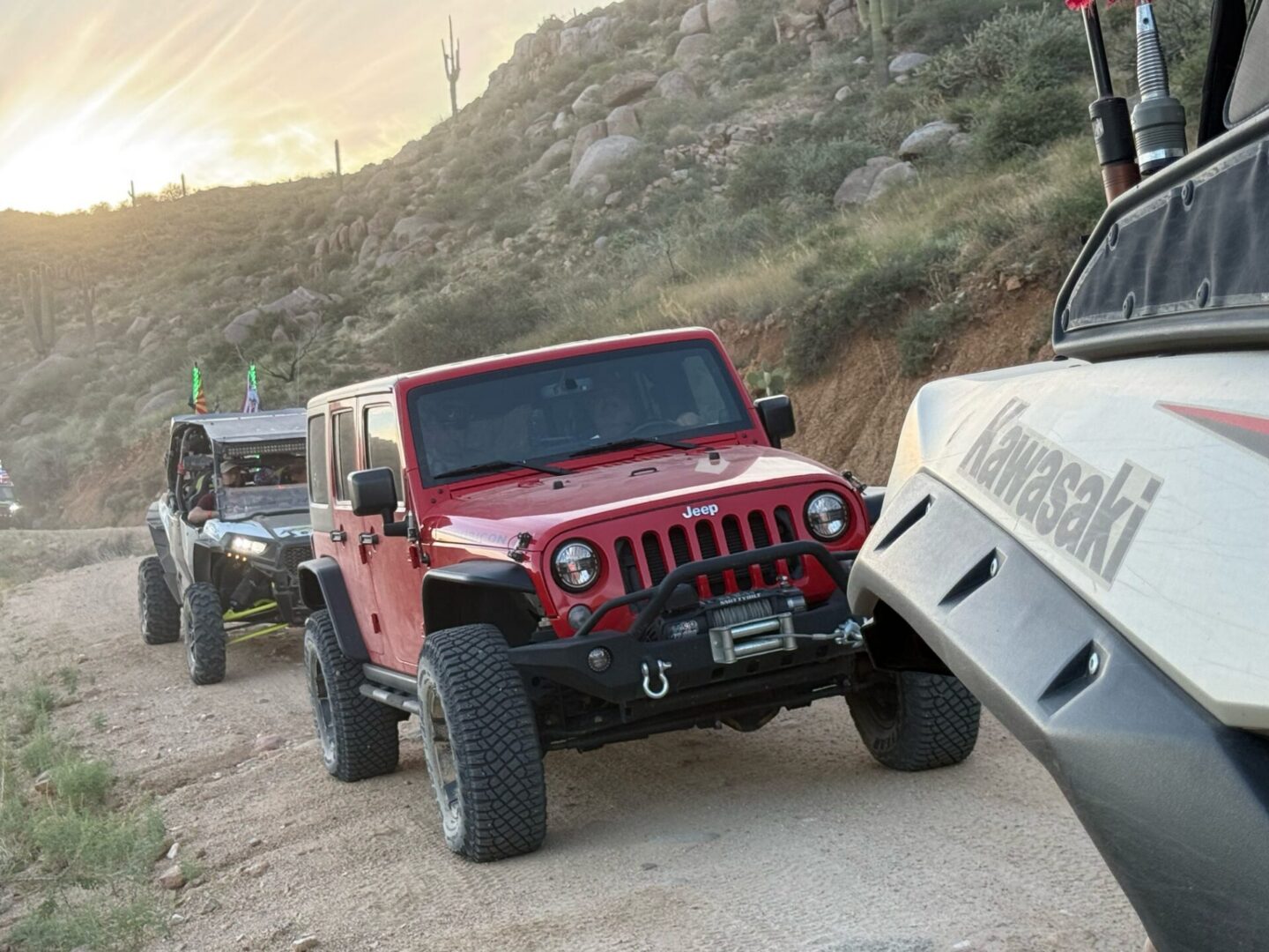 Red Jeep Wrangler and UTVs on desert trail