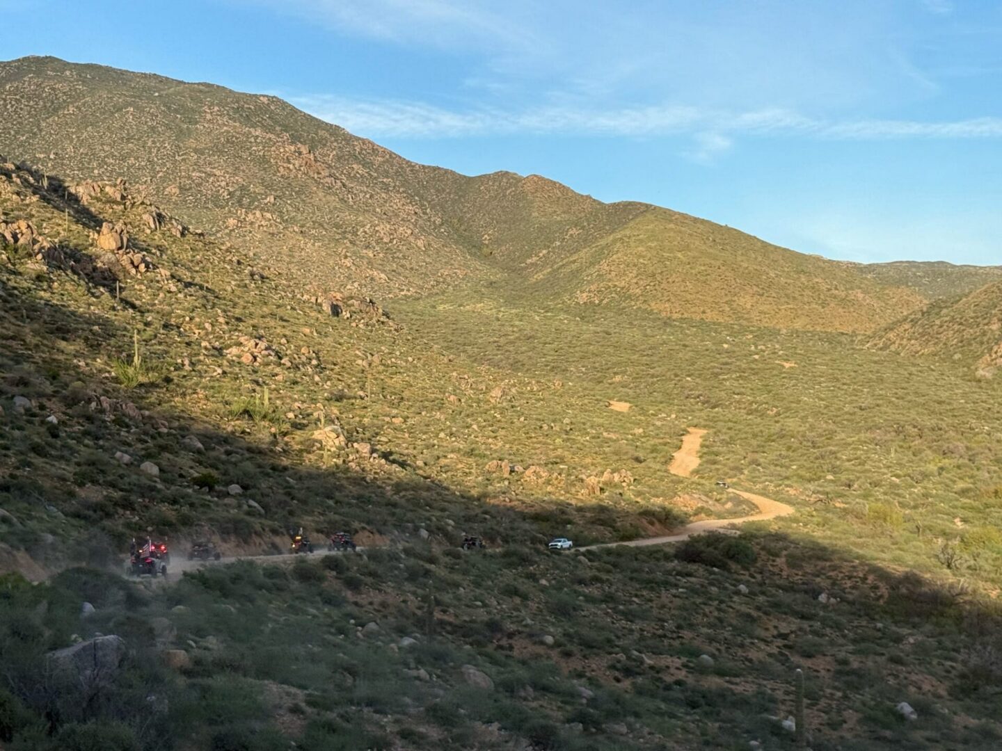 Winding dirt road through sunlit desert valley