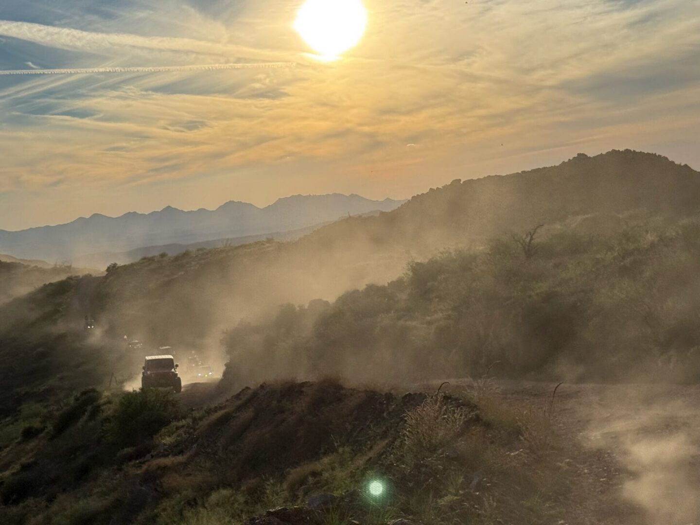 Sunlit dusty mountain road with SUV