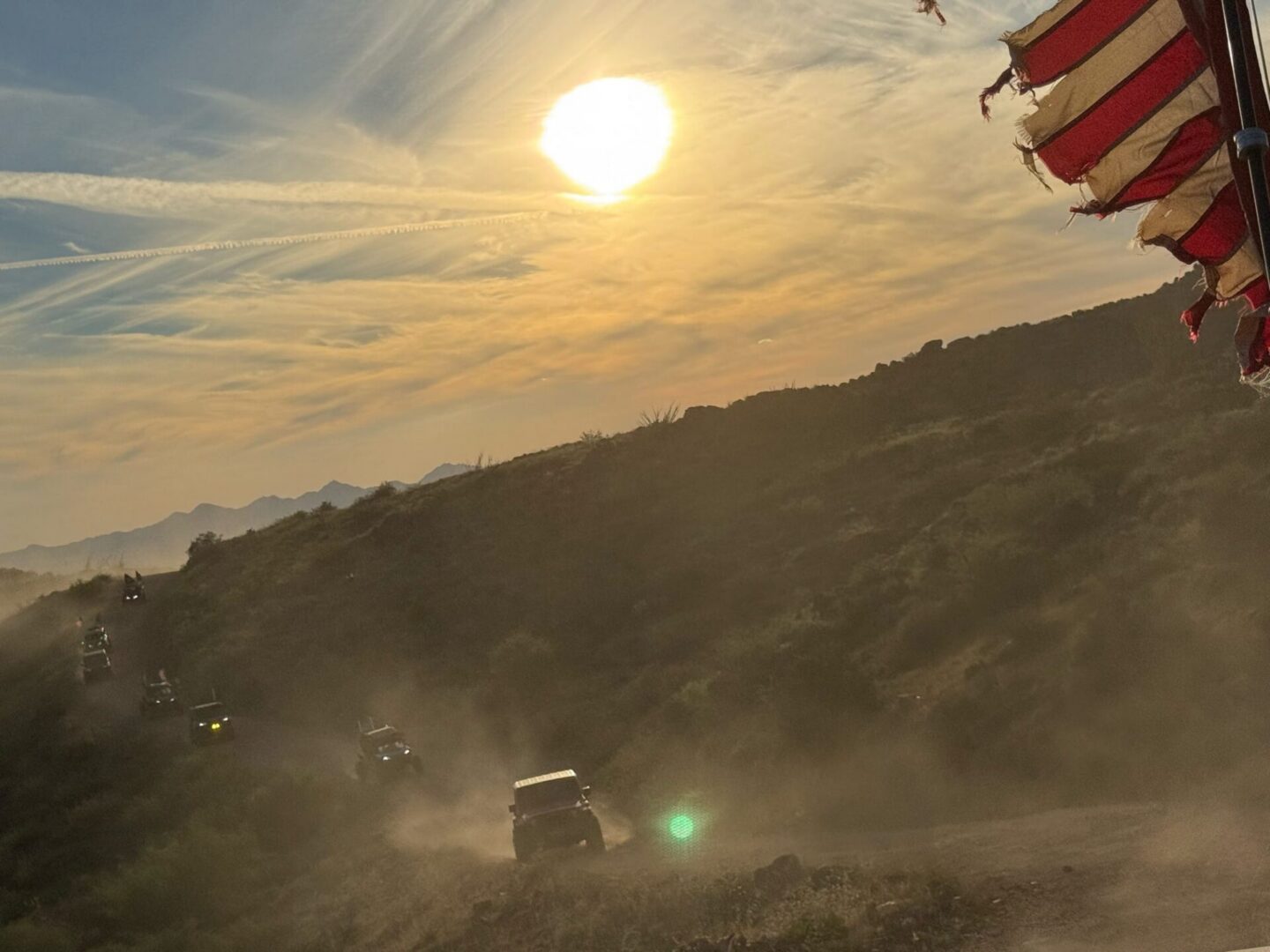 Off-road vehicles kicking up dust at sunset