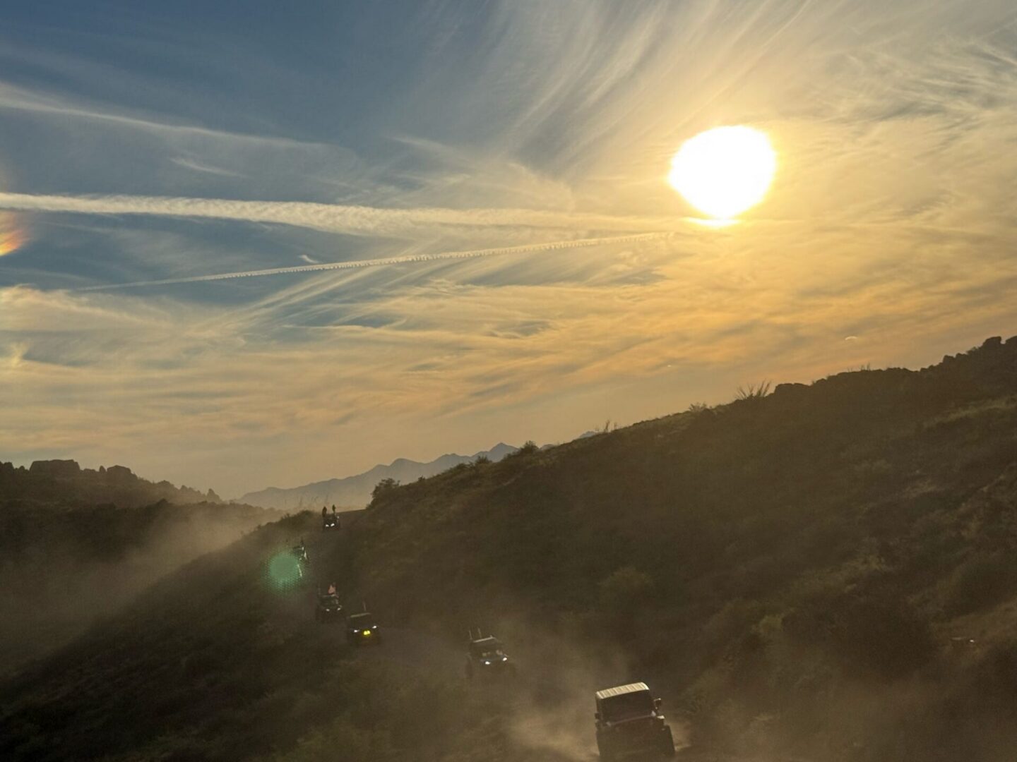 Sunset convoy of off-road vehicles kicking up dust