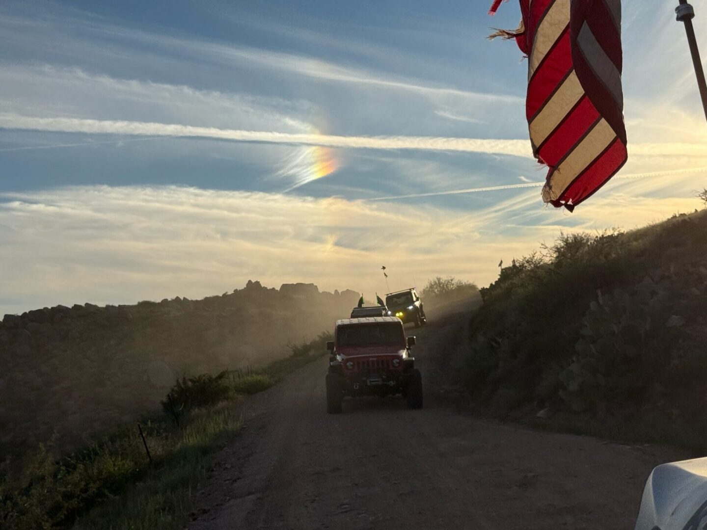 Jeep convoy on dusty road at sunset