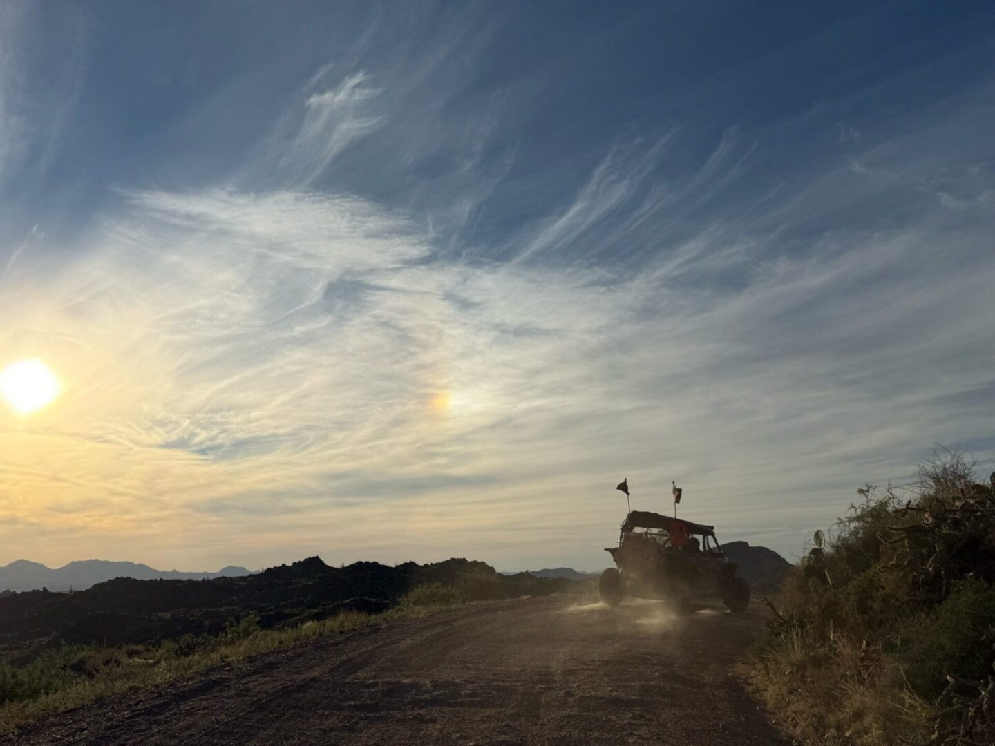 Off-road UTV on dusty dirt road at sunset