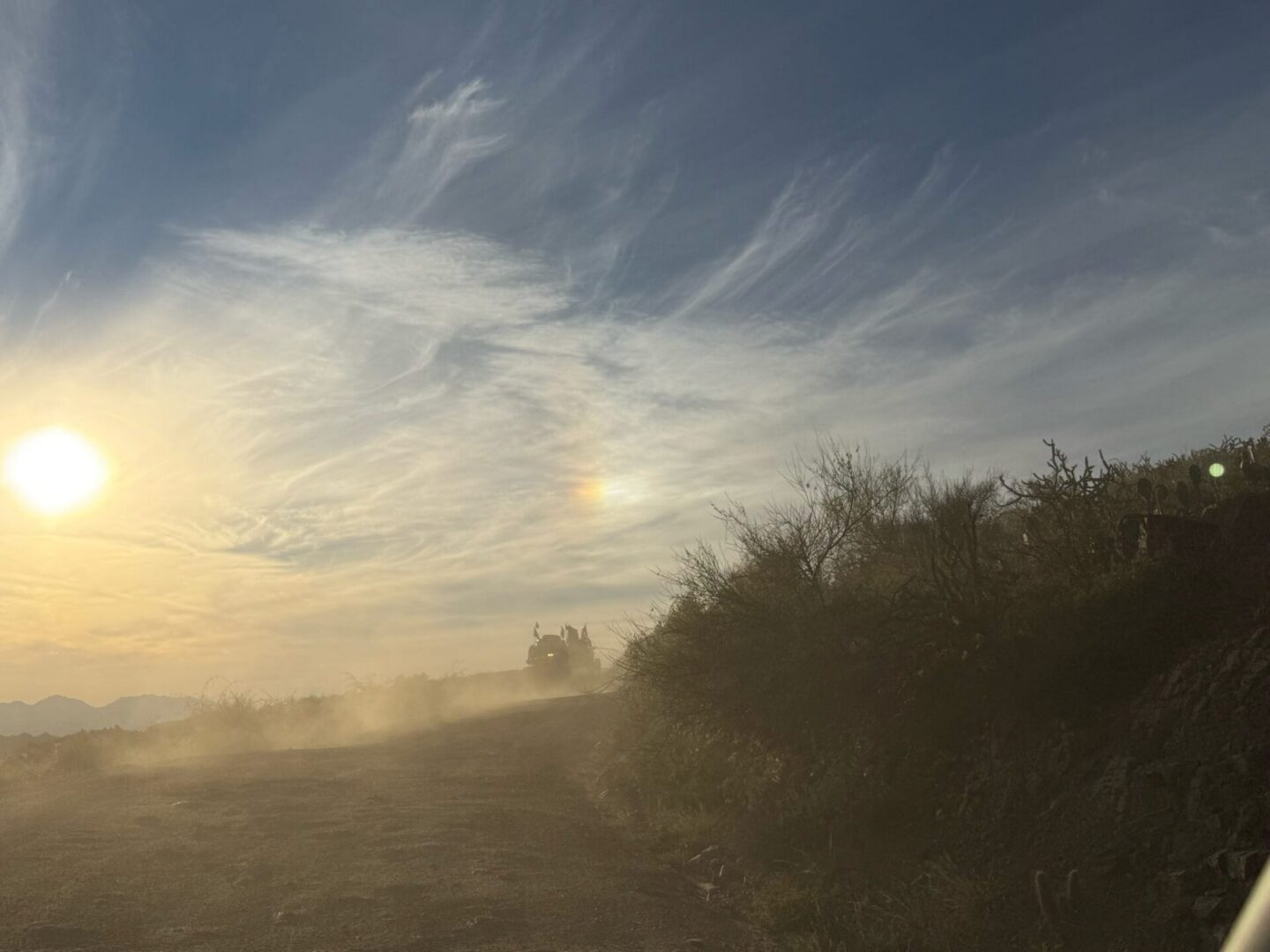 Sunset over dusty dirt road with bushes