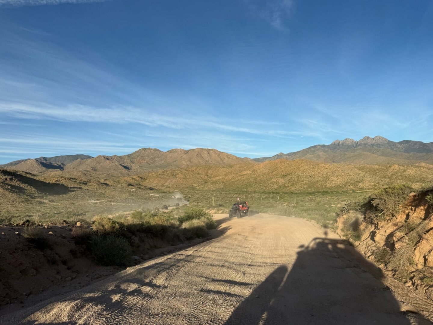 ATV driving on desert dirt road with mountains
