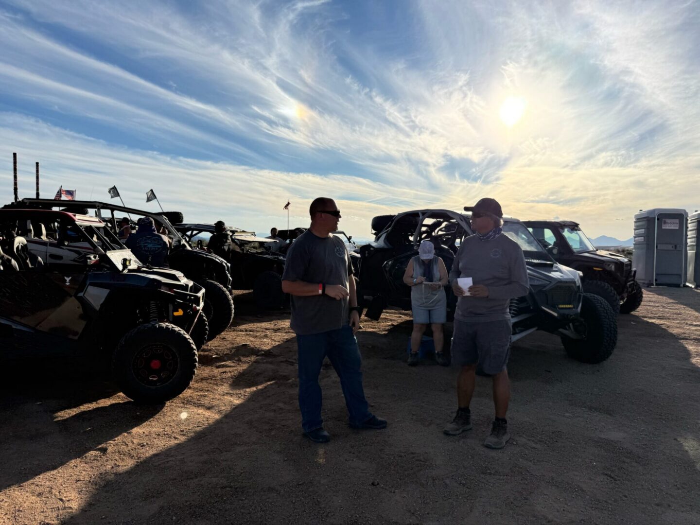 People standing by off-road vehicles under sun