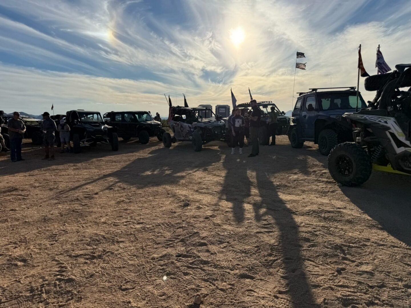 Off-road vehicles and people gathered at sunset