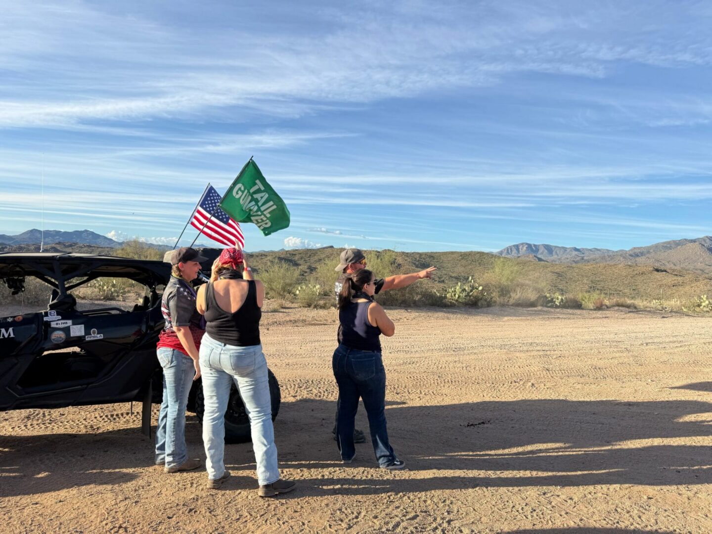 People by off-road vehicle holding flags in desert