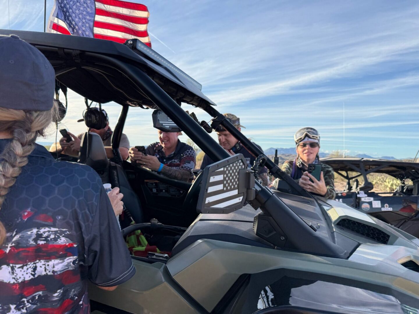 Group riding off-road UTV with American flag