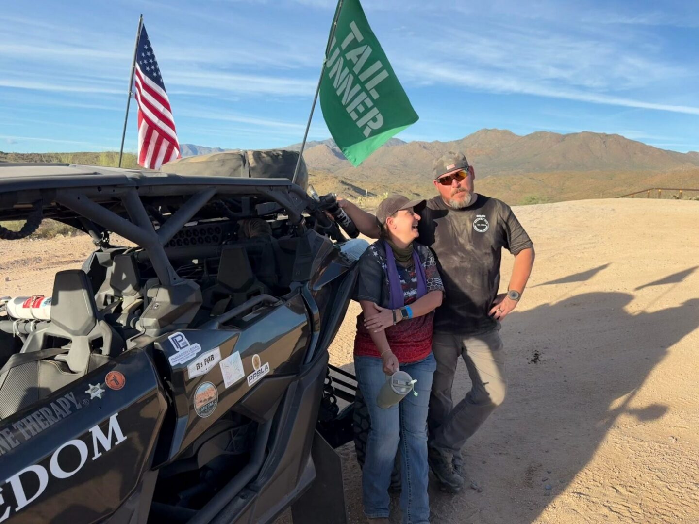 Two people by off-road vehicle with flags