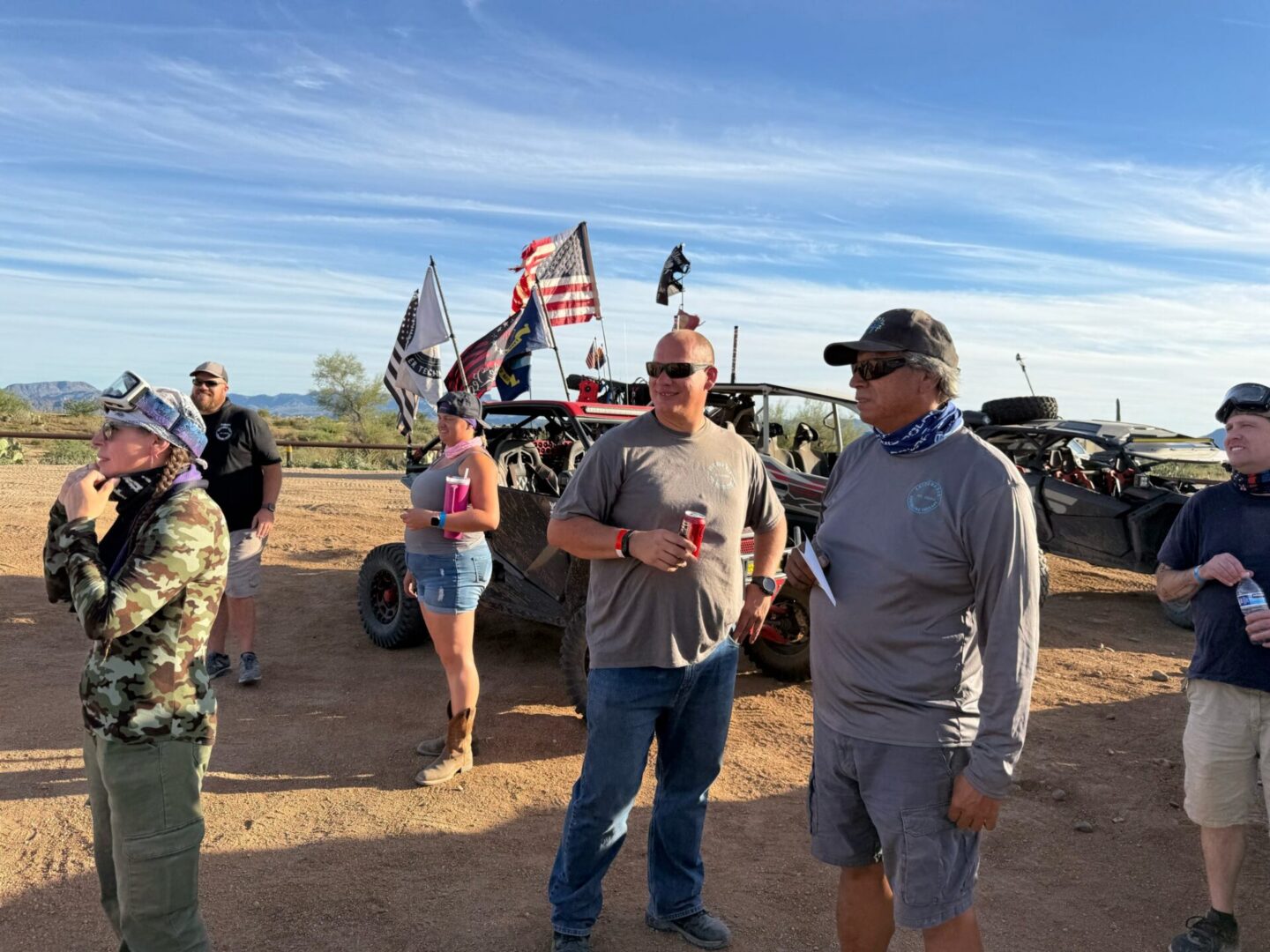 People gathered near off-road vehicles with flags