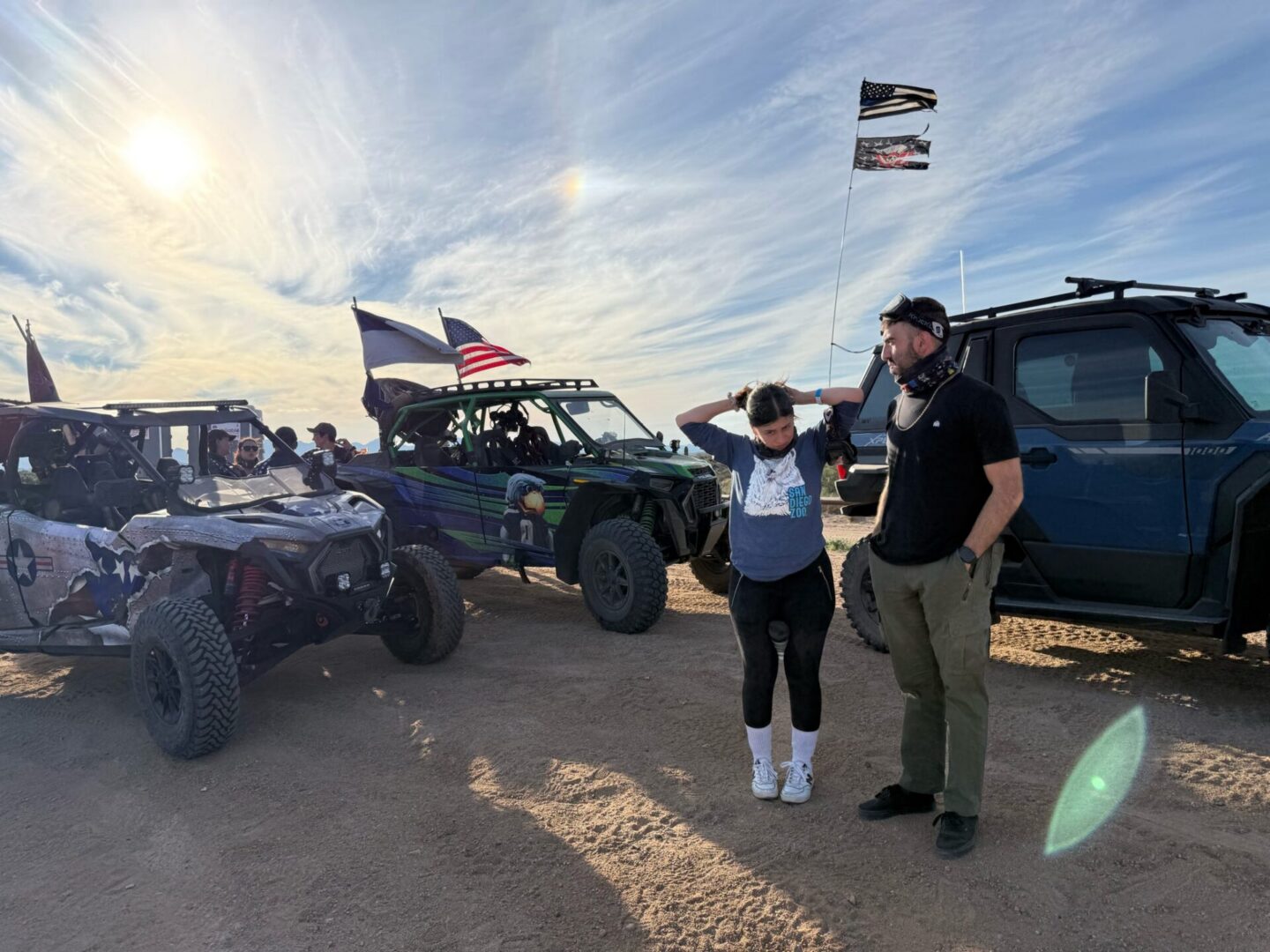 People beside off-road UTVs with flags
