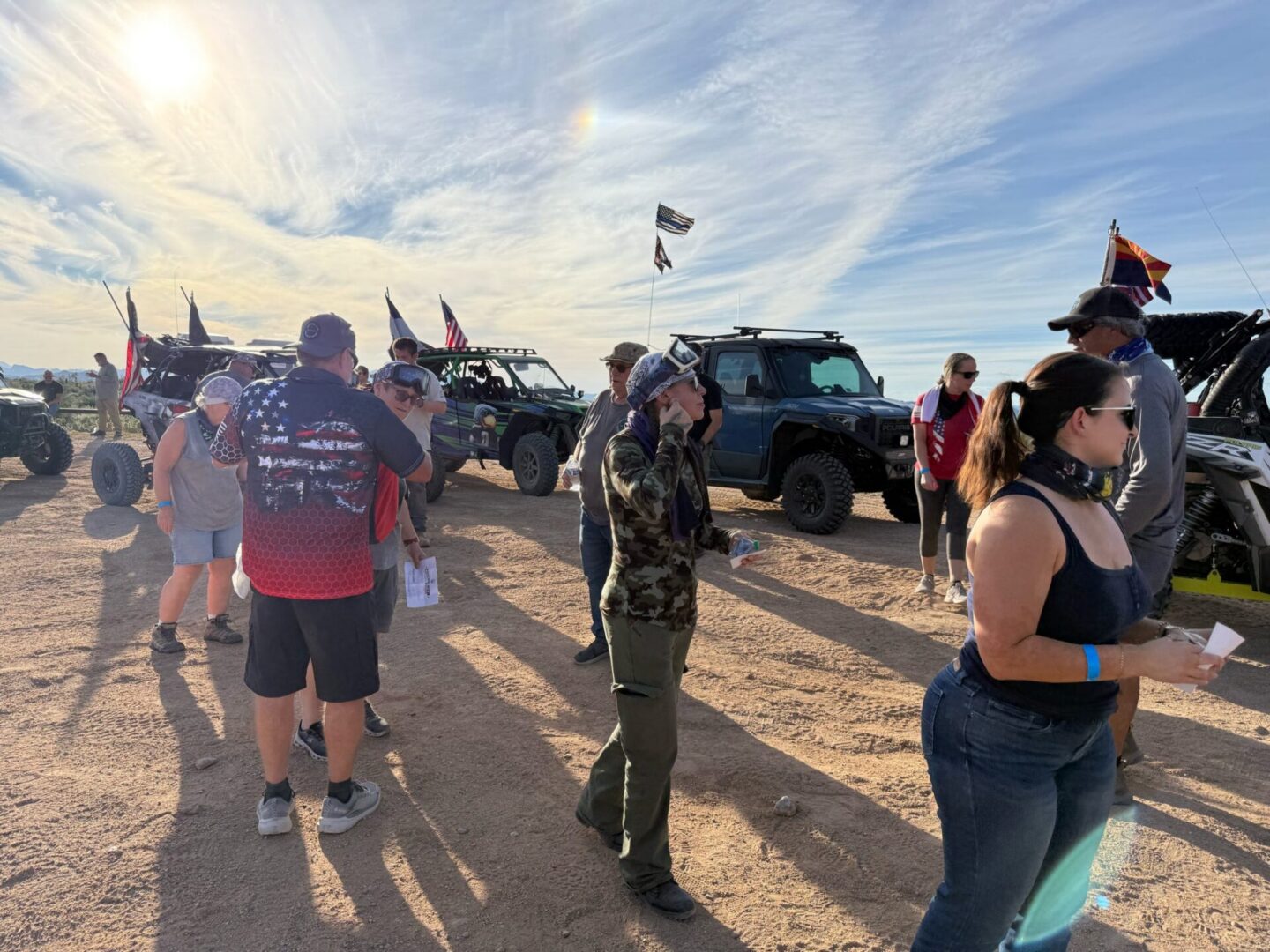 Group near off-road vehicles and flags in desert