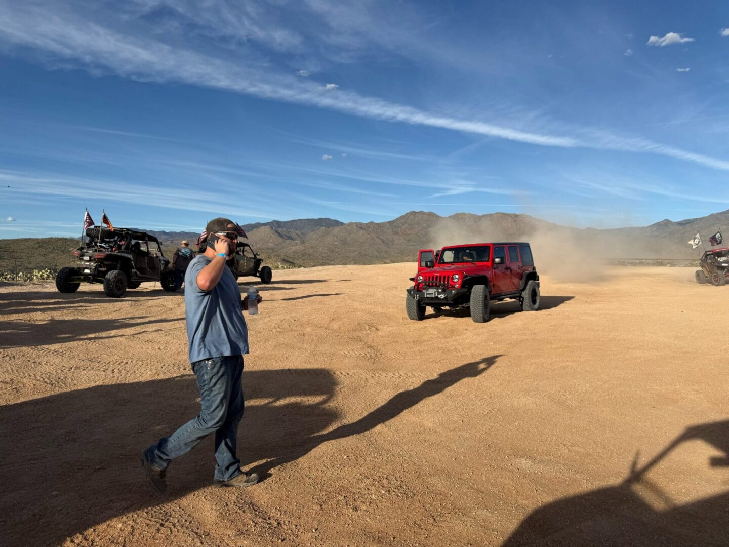 Red Jeep kicking up dust in desert