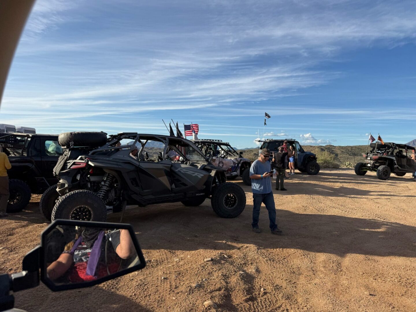 Off-road UTVs parked in desert with people