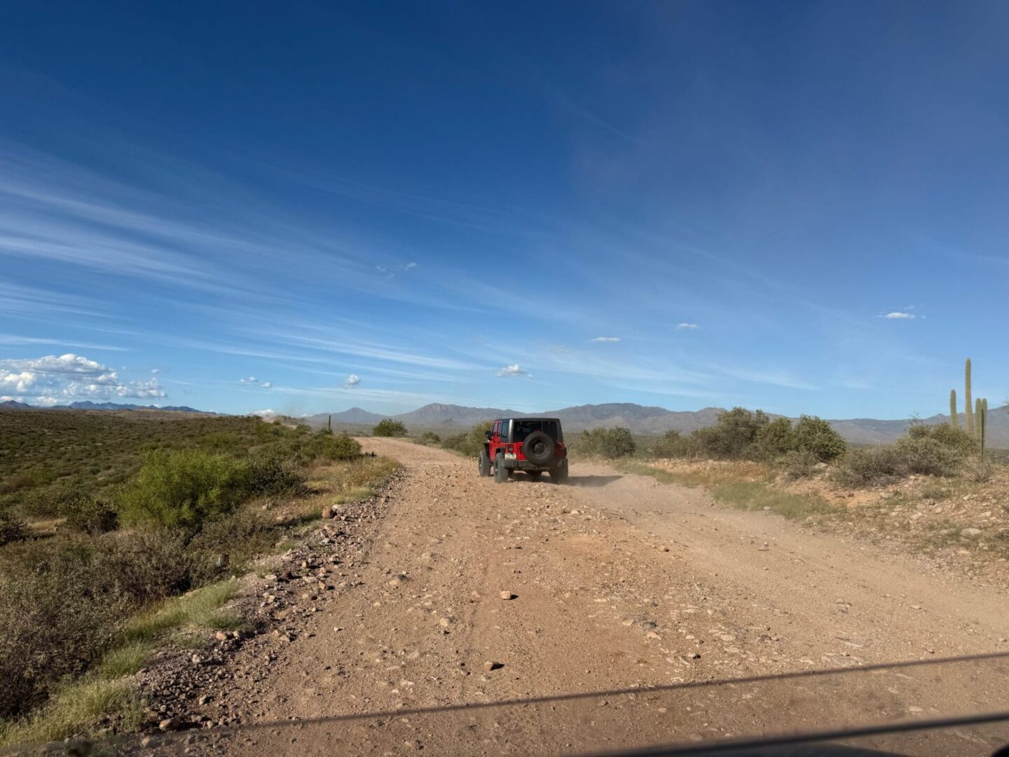 Red Jeep driving on dusty desert road