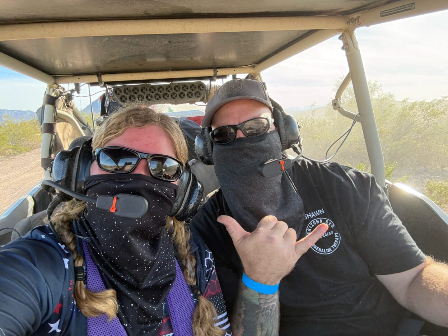 Two masked riders in desert dune buggy