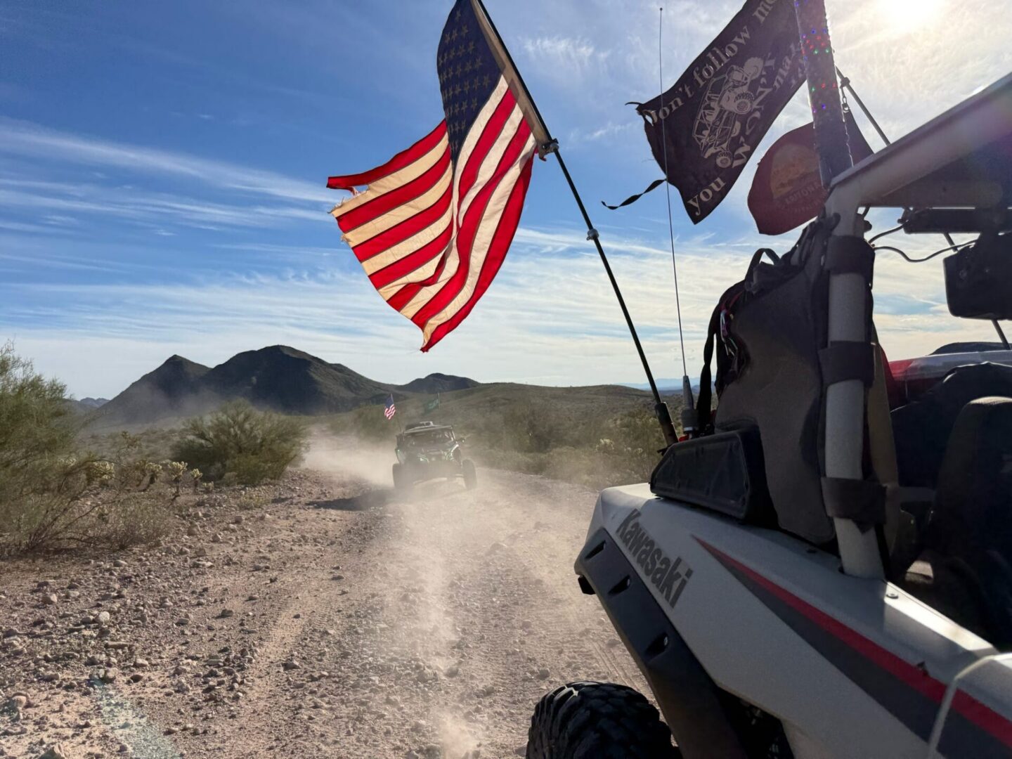 UTV convoy on desert trail with American flag