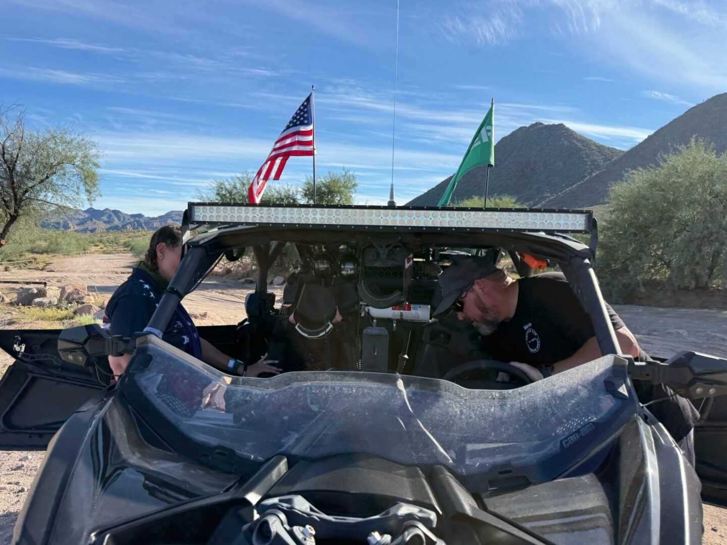 UTV with two people, dog, and flags