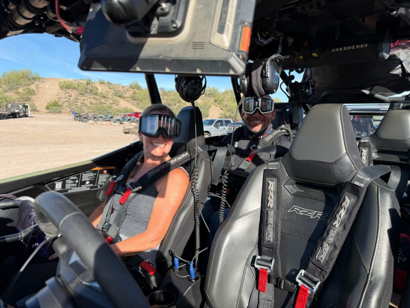 Two people wearing goggles inside off-road vehicle