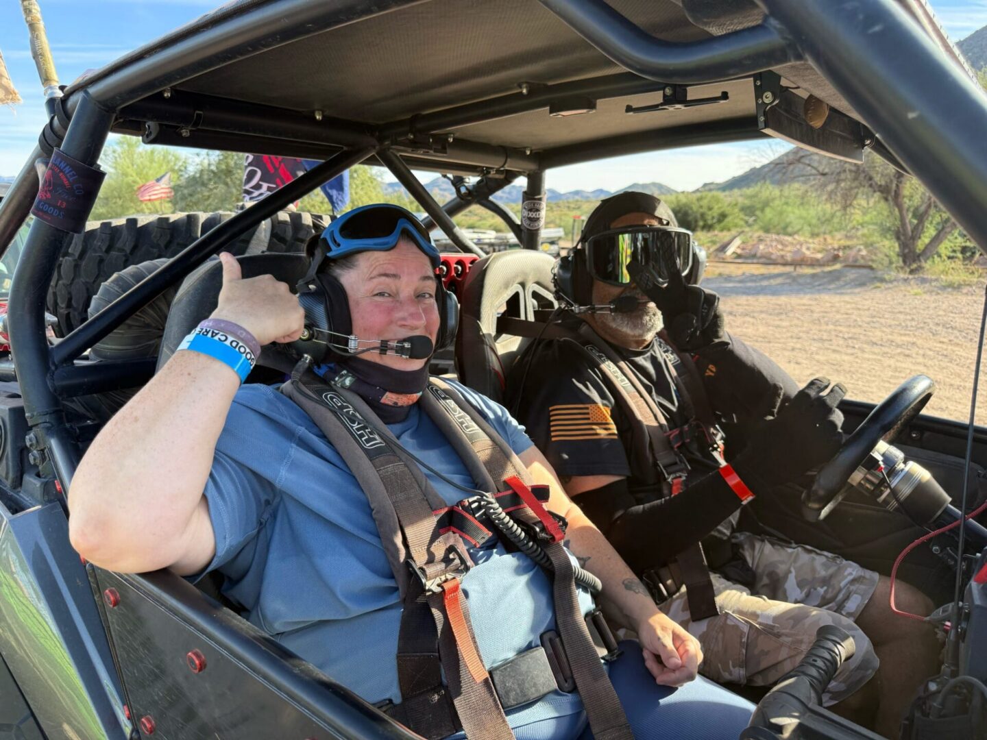 Two people in off-road buggy, one thumbs-up