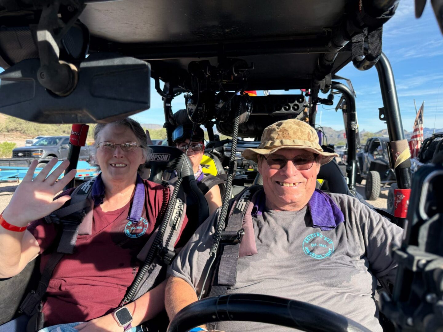 Smiling couple in side-by-side UTV waving