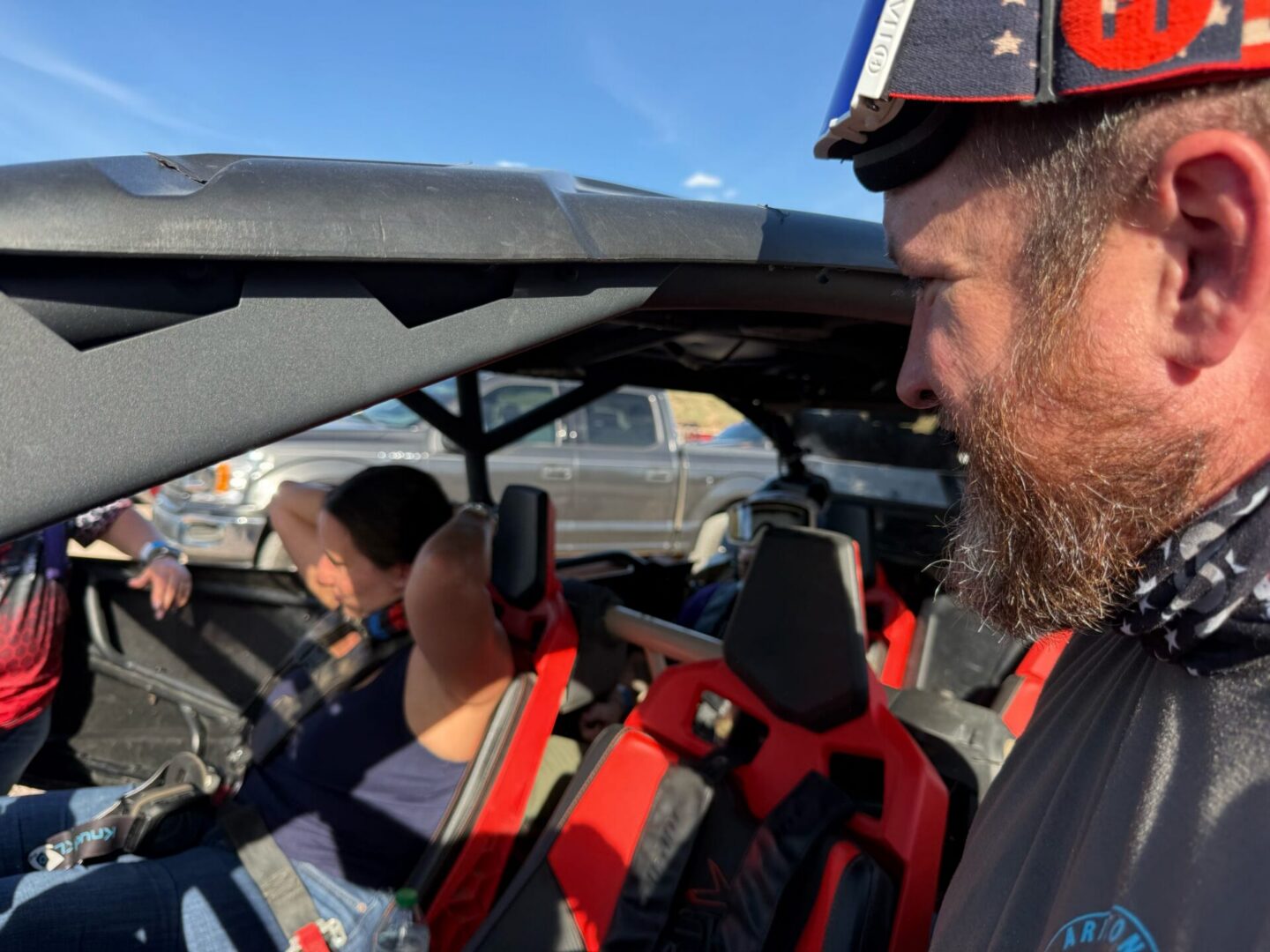 Bearded man beside off-road vehicle with passenger