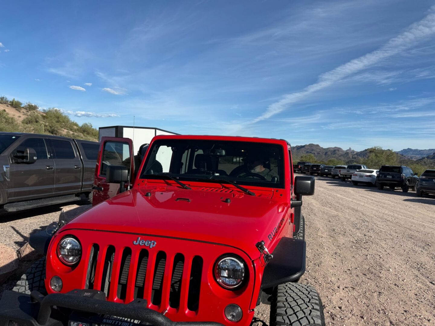 Red Jeep Wrangler parked on gravel lot