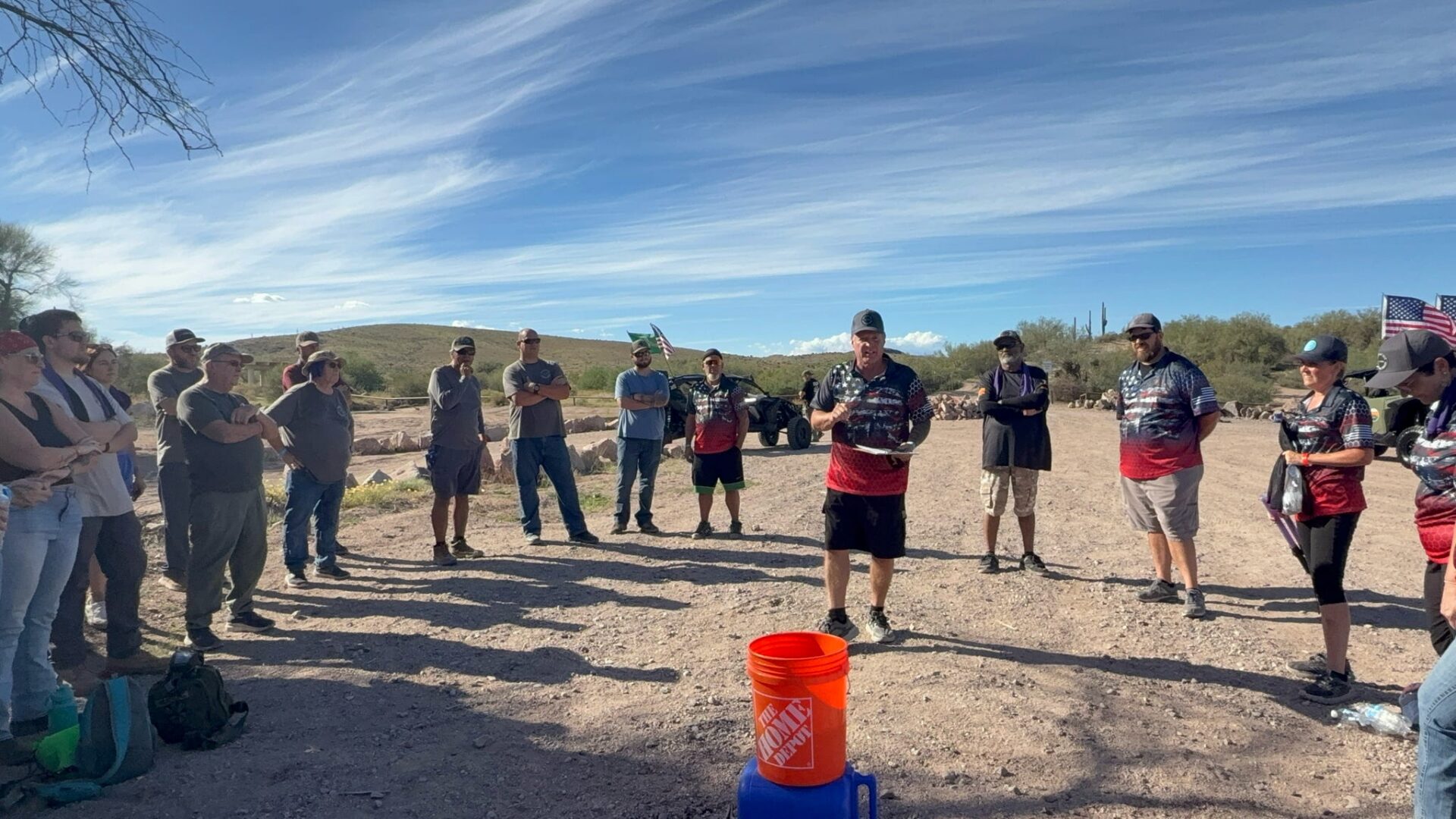 Outdoor group gathered around orange bucket in desert