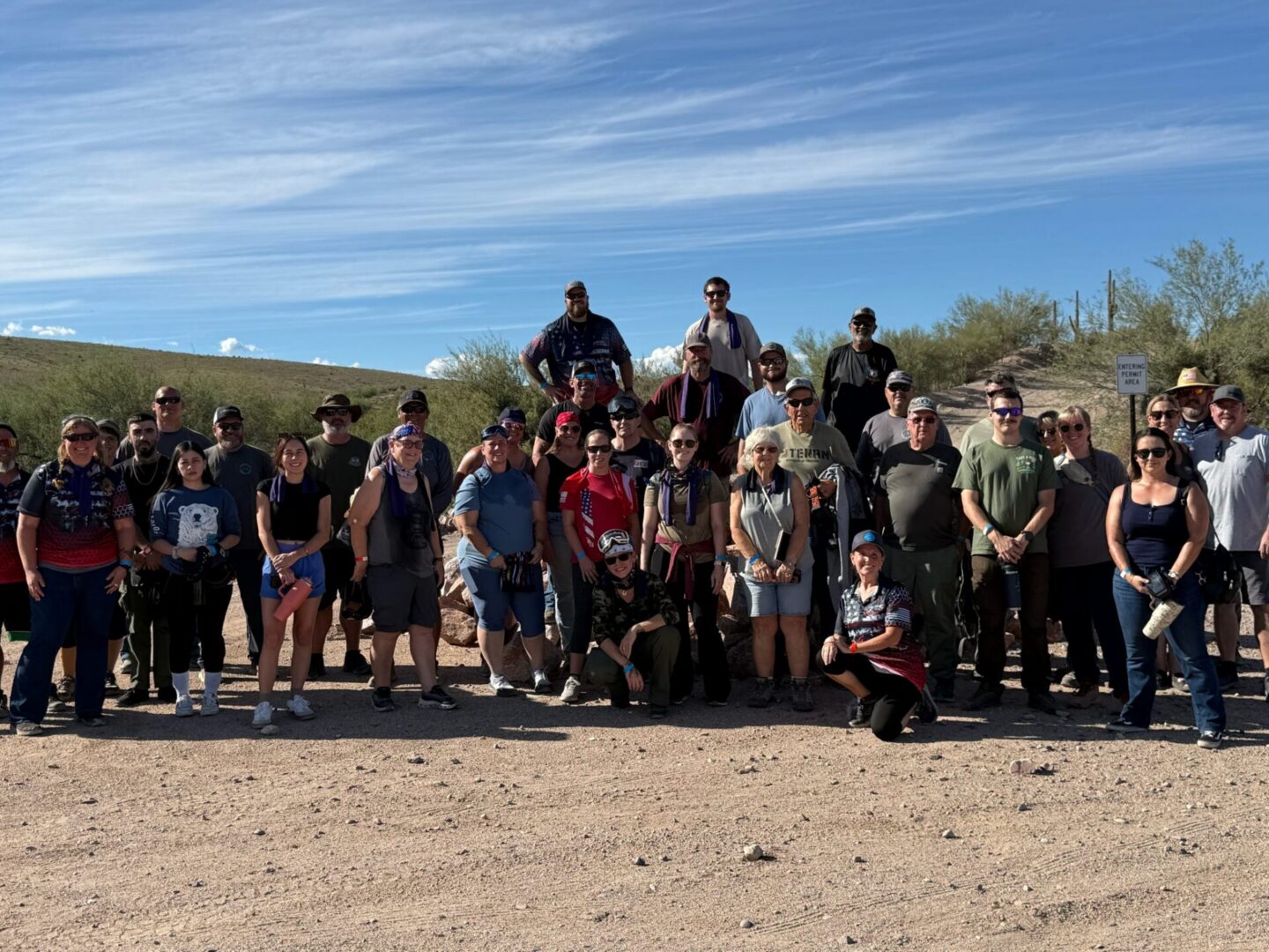 Large group posing on sunny desert trail
