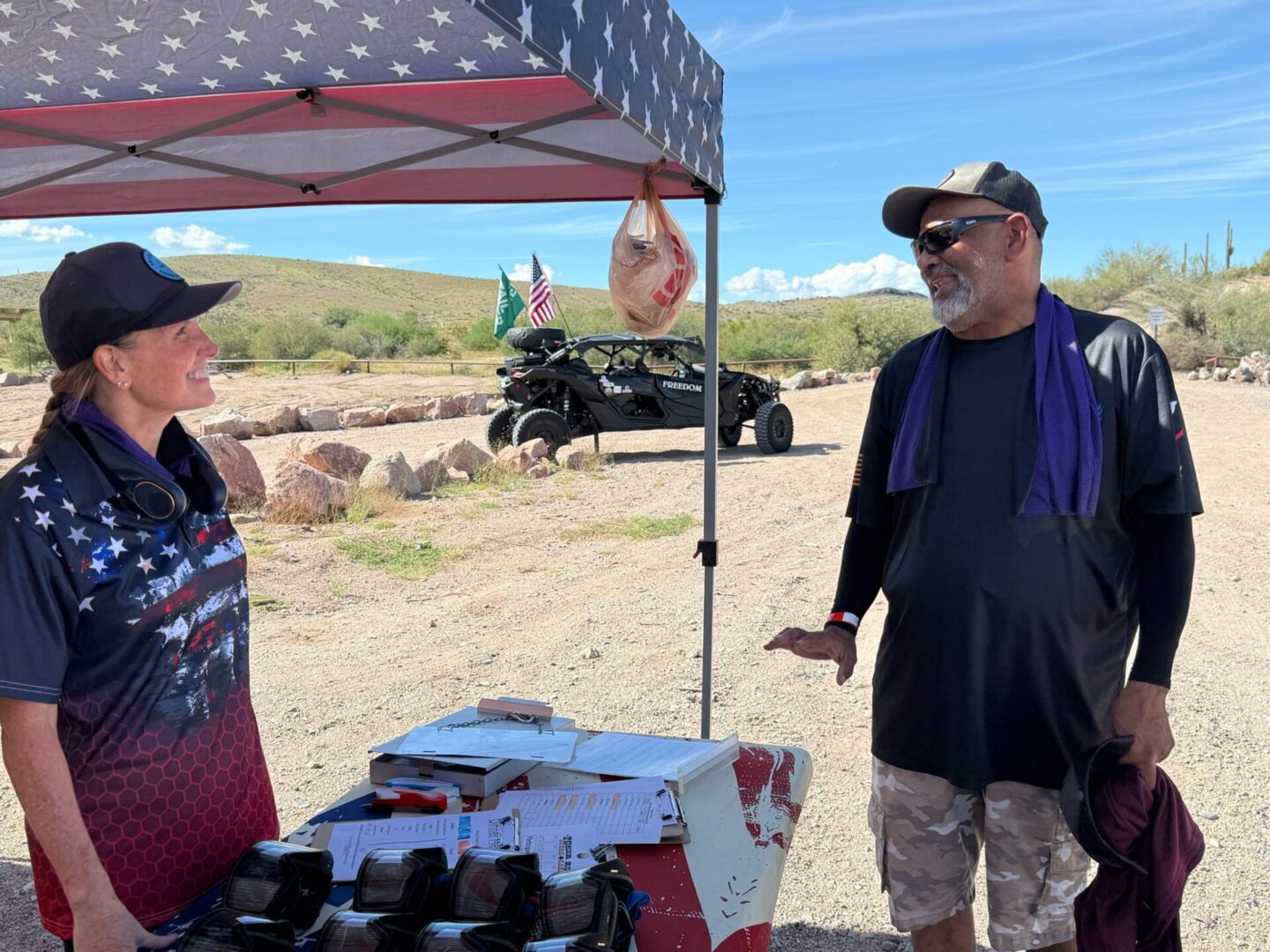 Two people at American-flag canopy registration table