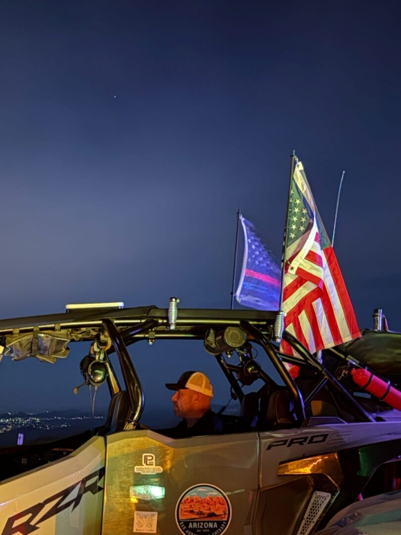UTV driver at dusk with American flags