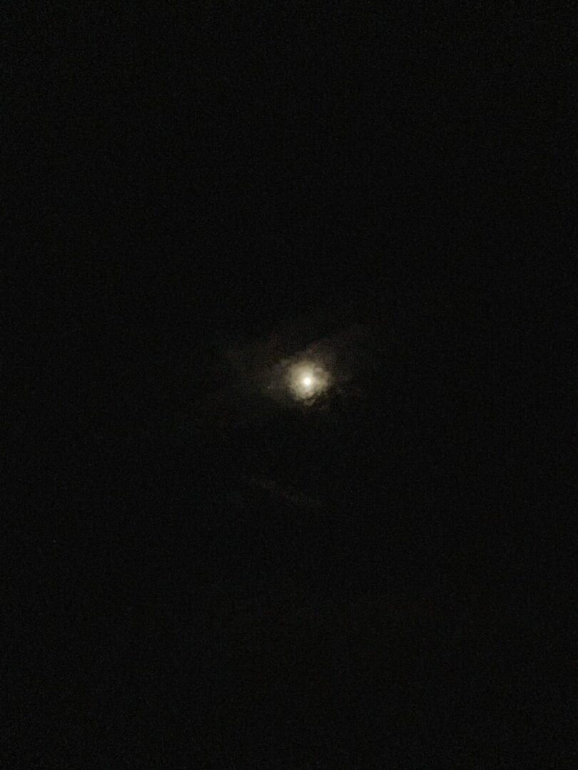 Moon glowing through thin night clouds
