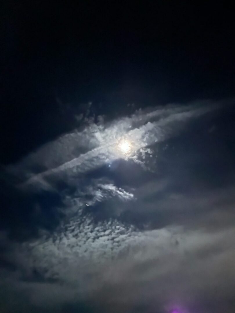 Moon shining through wispy cloudy night sky