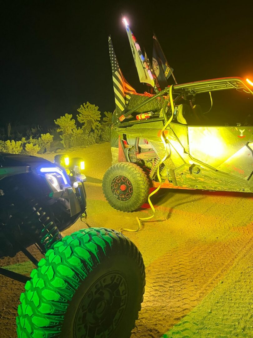 Two illuminated off-road vehicles with flags