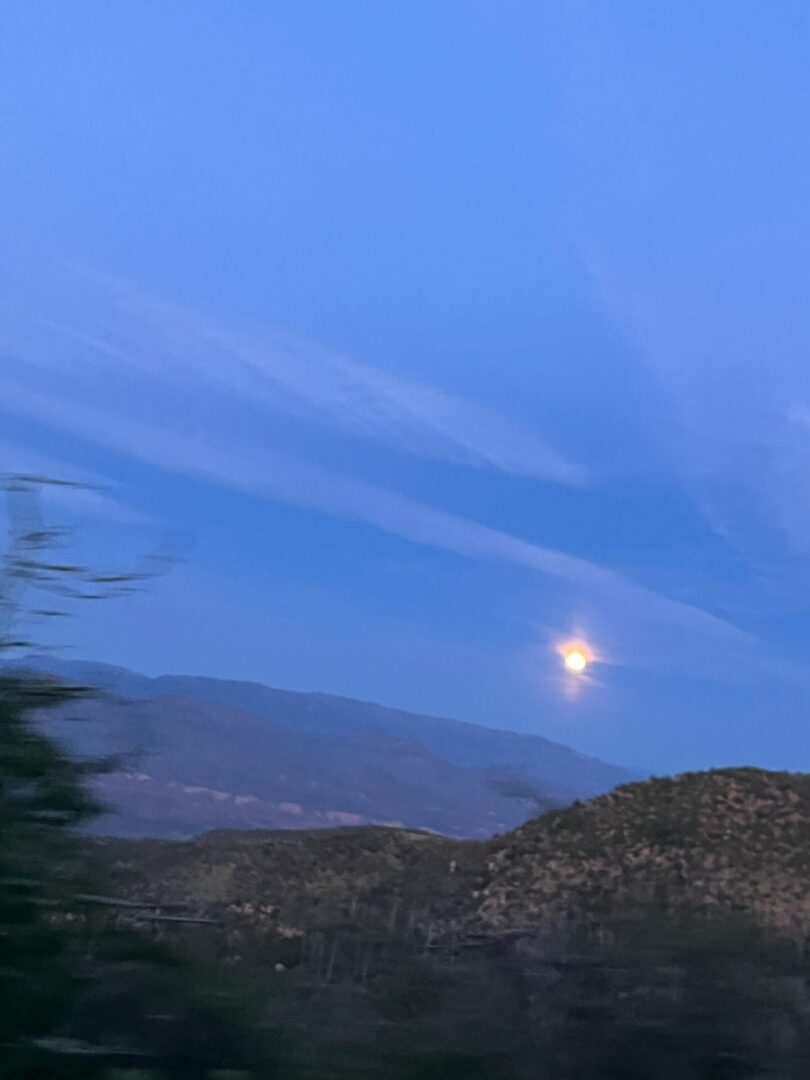 Moon rising above hills at twilight