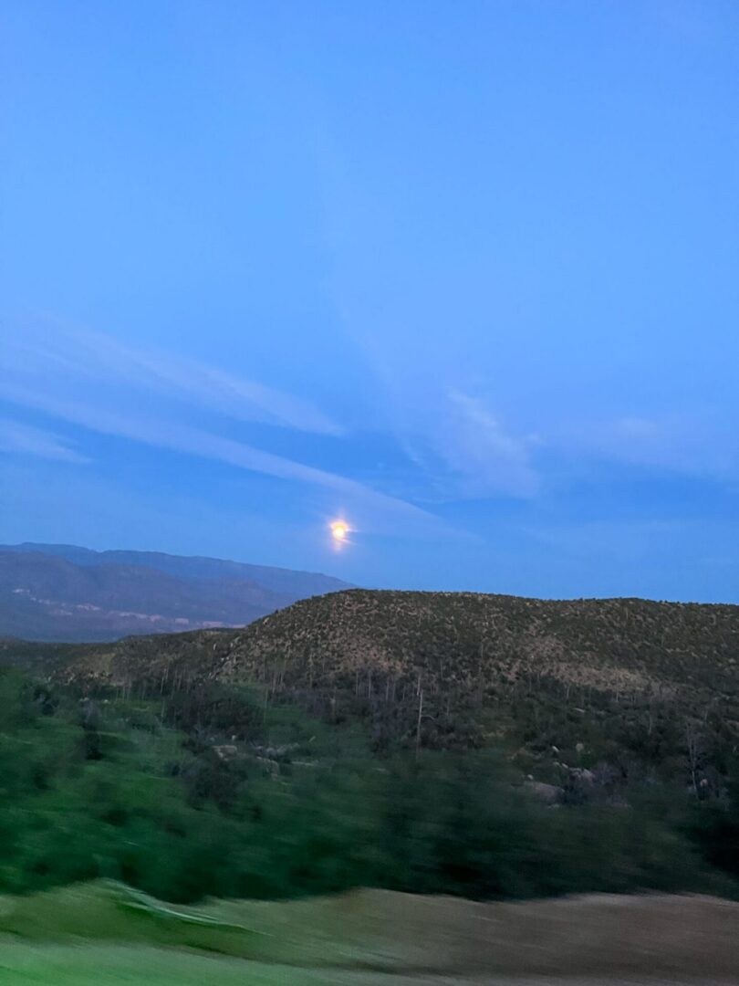 Moonrise above rolling hills at dusk