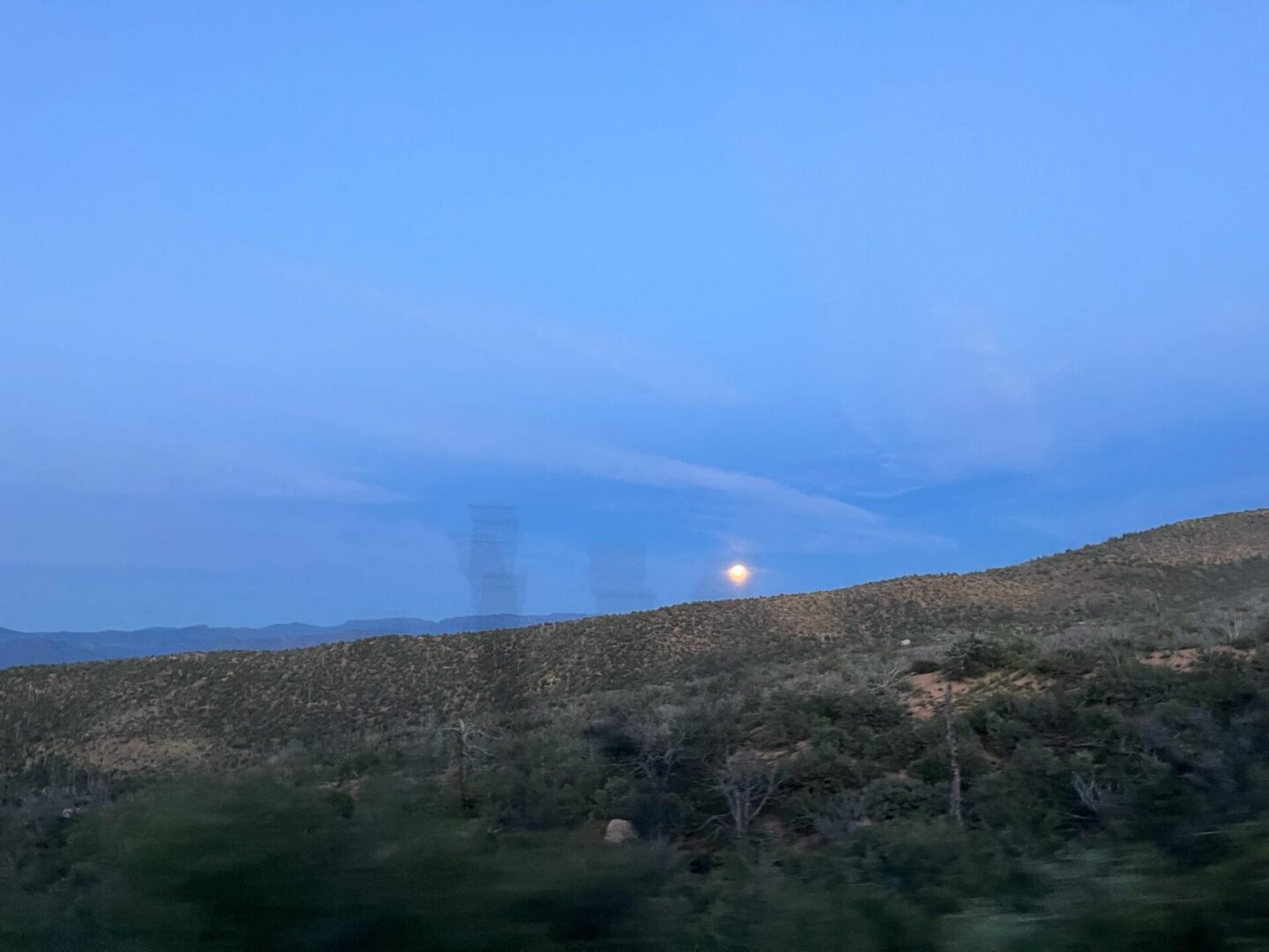 Moonrise over desert hills at dusk