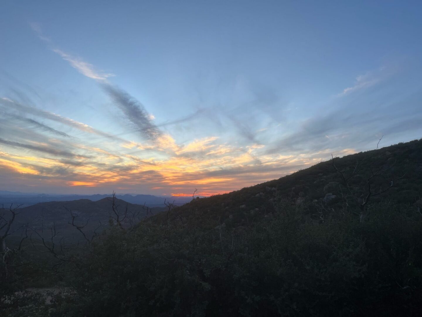 Sunset over rolling hills with streaked clouds