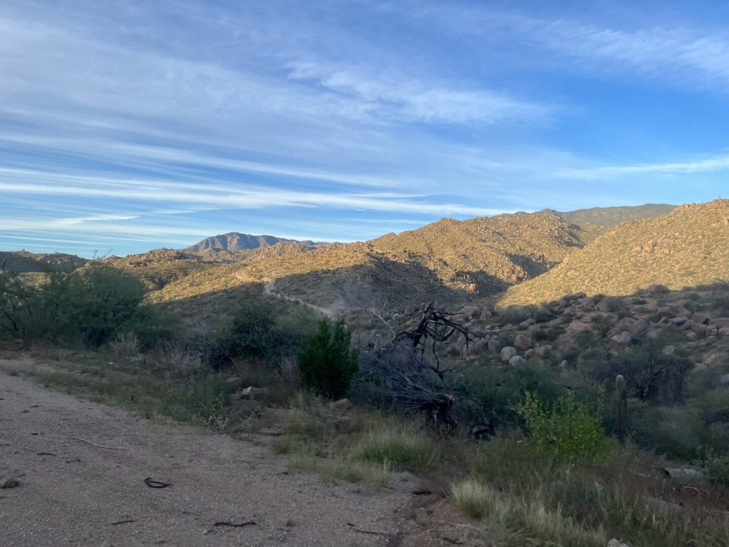 Sunlit desert hills under streaked blue sky