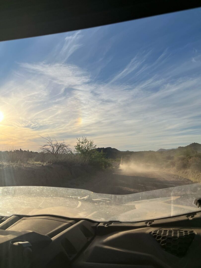 Sunlit view from vehicle on dusty dirt road
