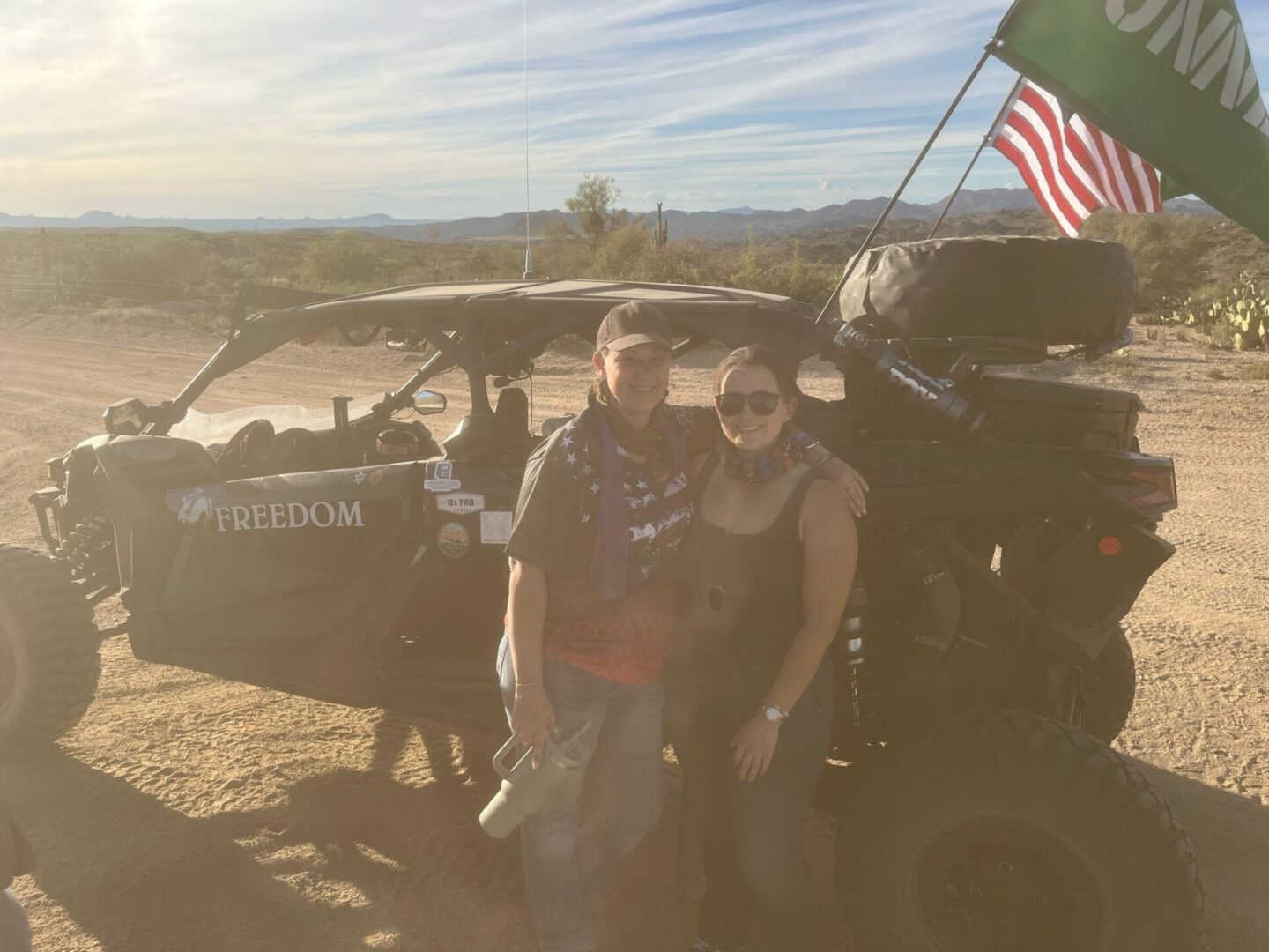Two people by desert UTV with American flag