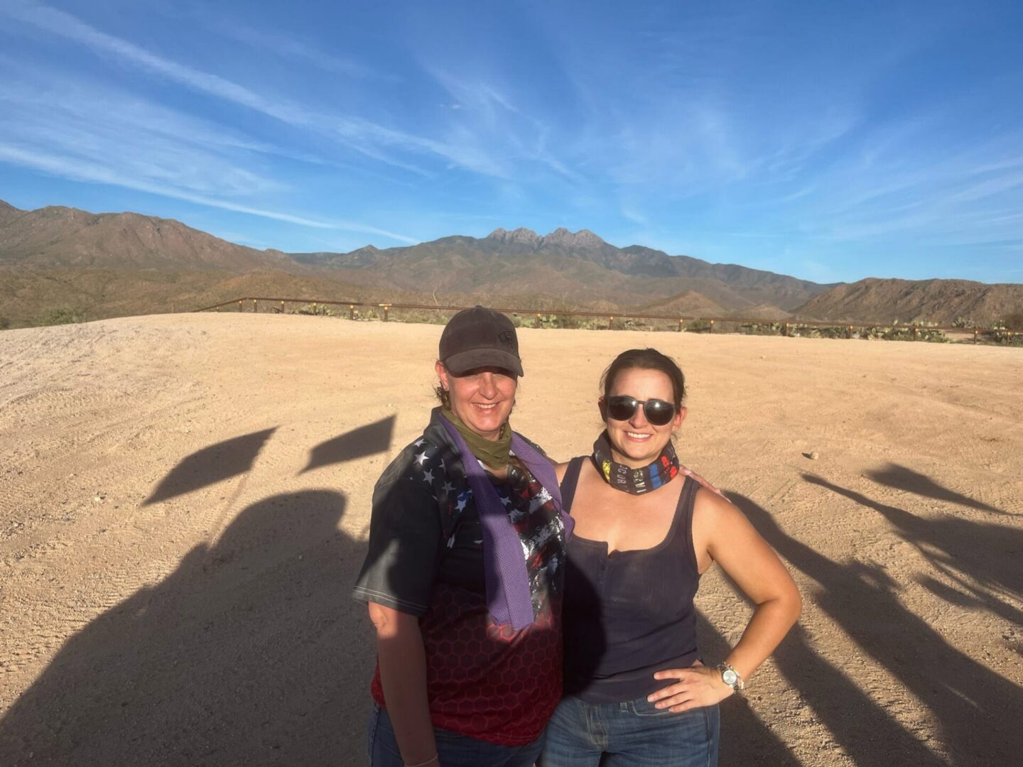 Two smiling people on desert plain with mountains
