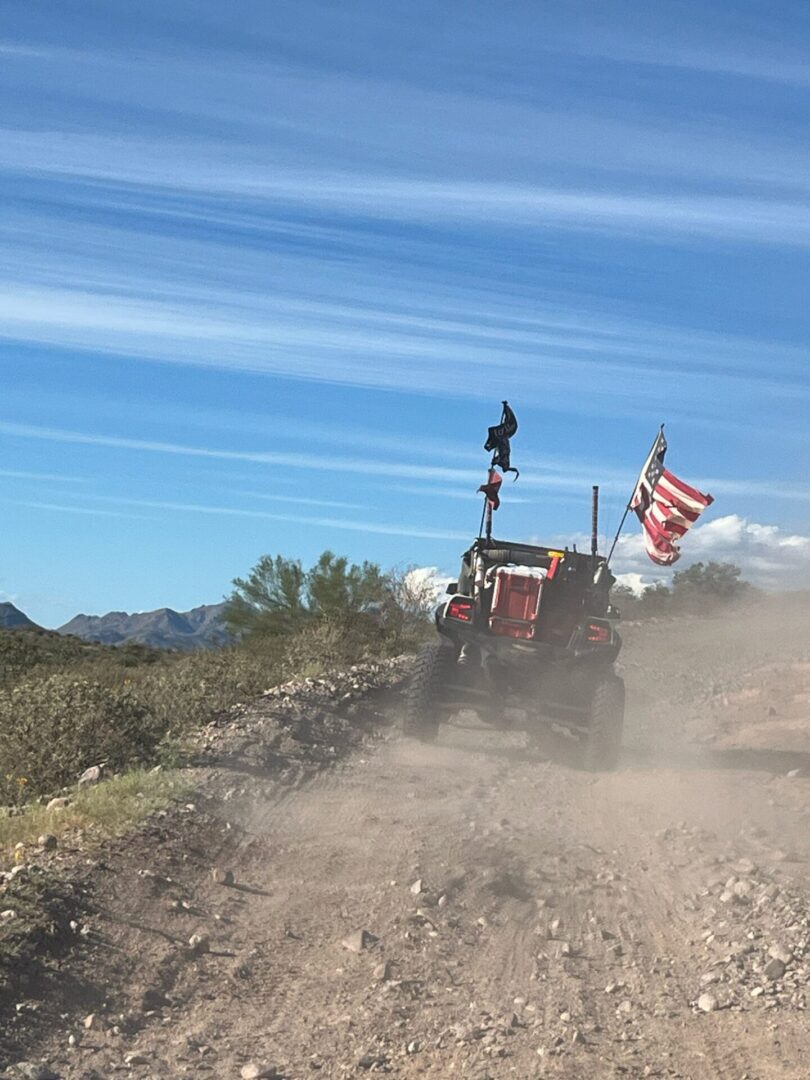 Off-road vehicle kicking up dust with American flag