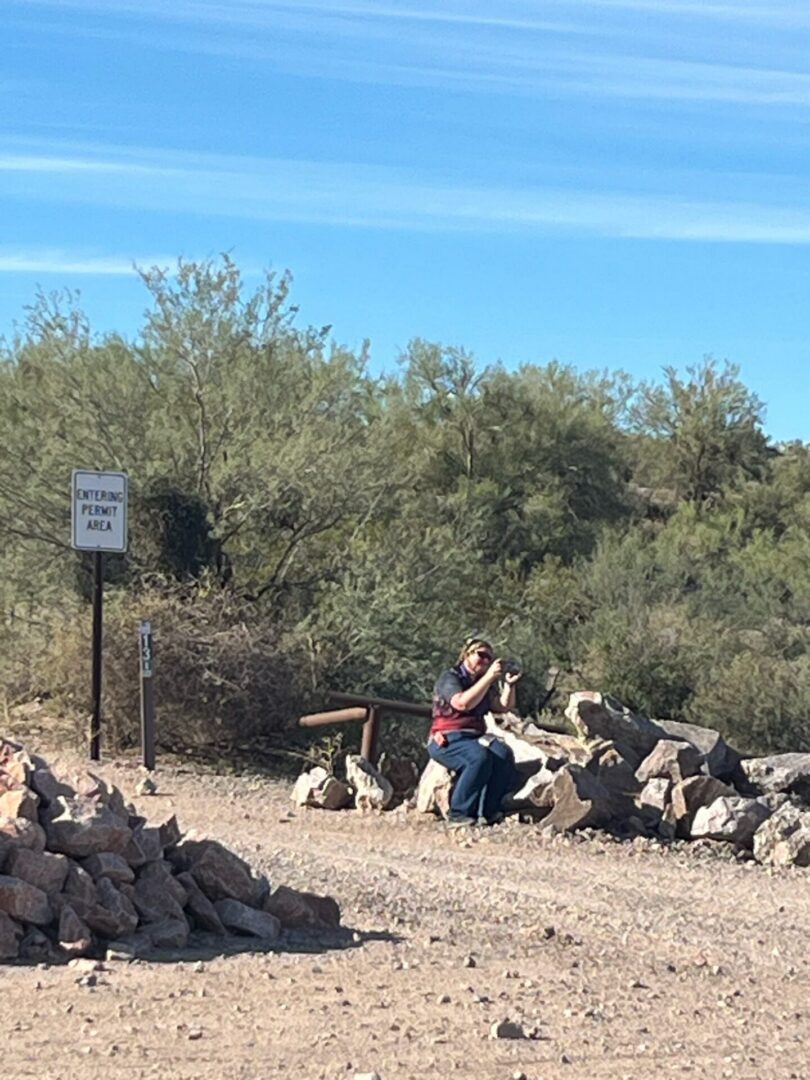 Person crouching by rocks in desert landscape