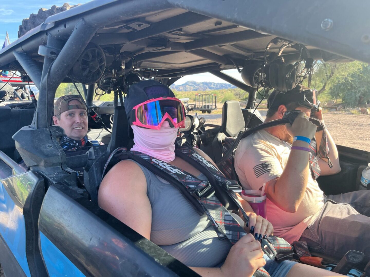 Three people wearing goggles in off-road buggy