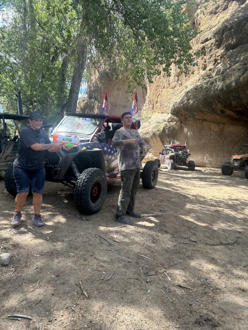 People beside off-road UTVs near rock cliff