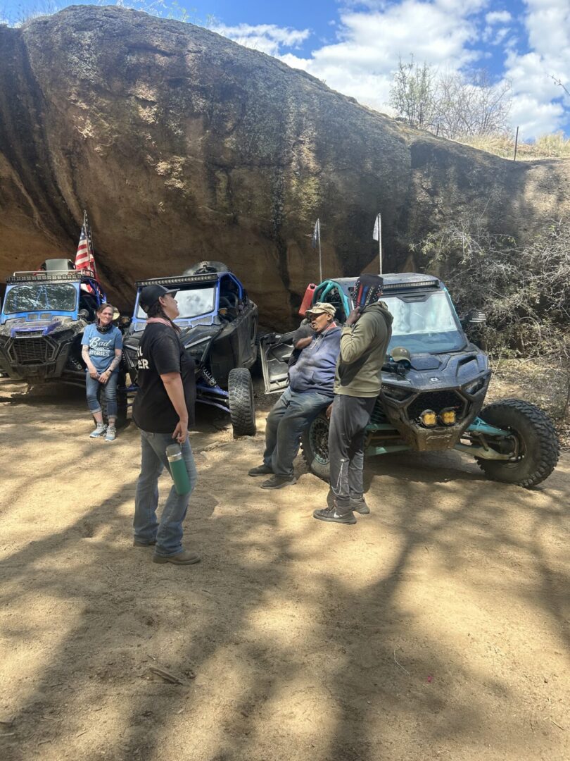 Group of people with UTVs by boulder