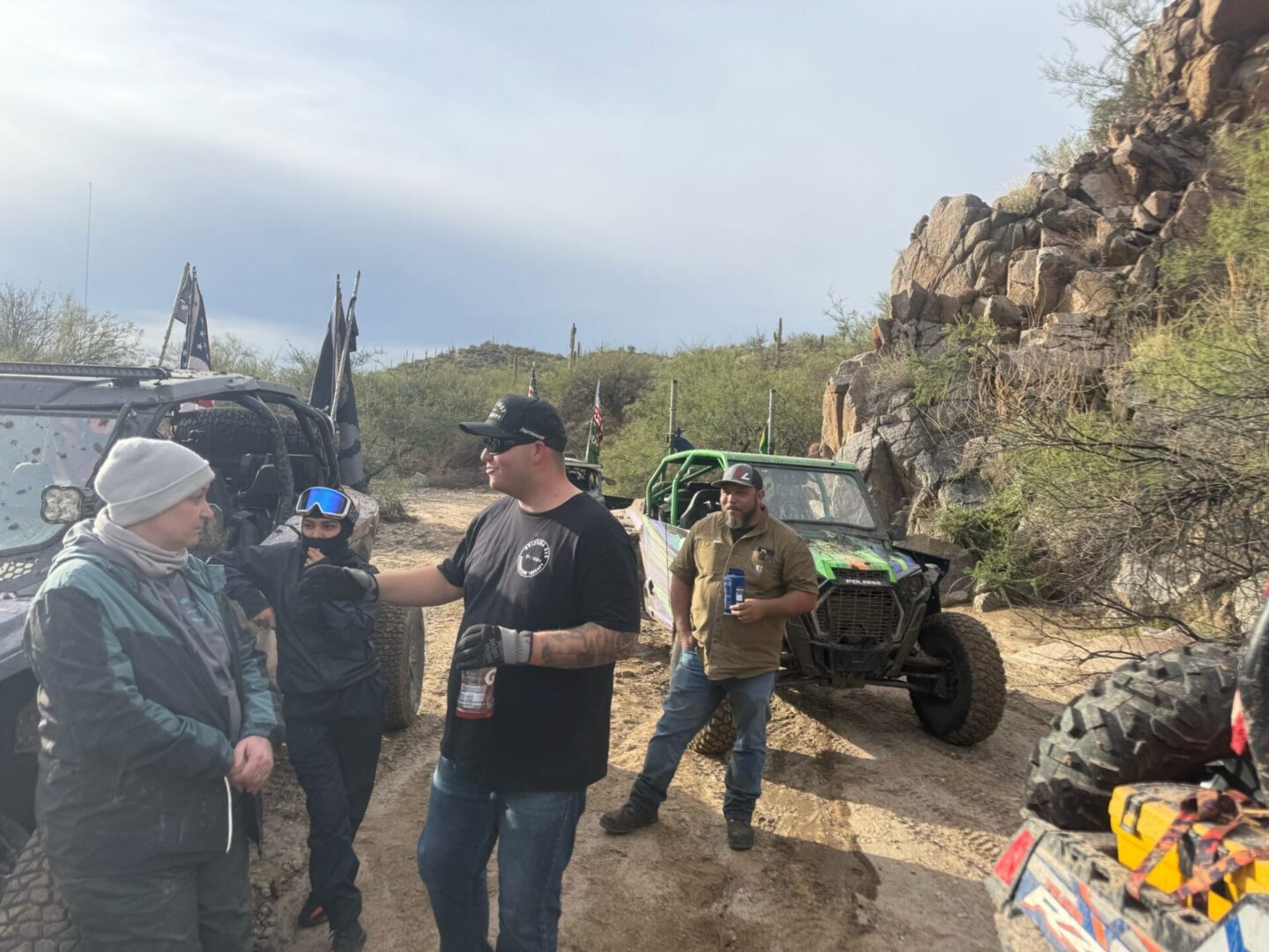 Group chatting beside off-road vehicles in desert